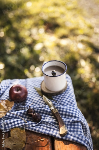 Coffee, apple, grapes and autumn leaves on wooden bench photo