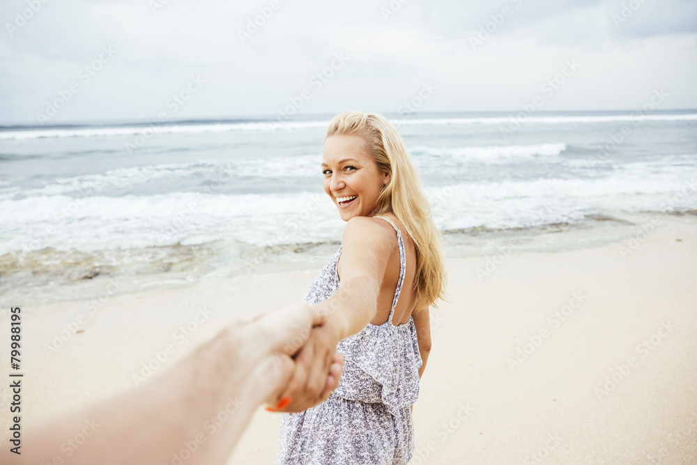 Indonesia, Bali, smiling woman on beach pulling hand of a man Indonesia, Bali, smiling woman on beach pulling hand of a man