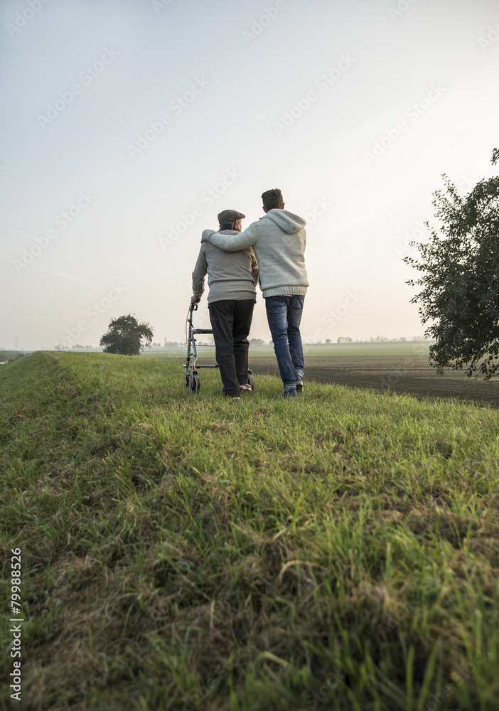 Senior man and grandson in rural landscape with wheeled walker Senior man and grandson in rural landscape with wheeled walker