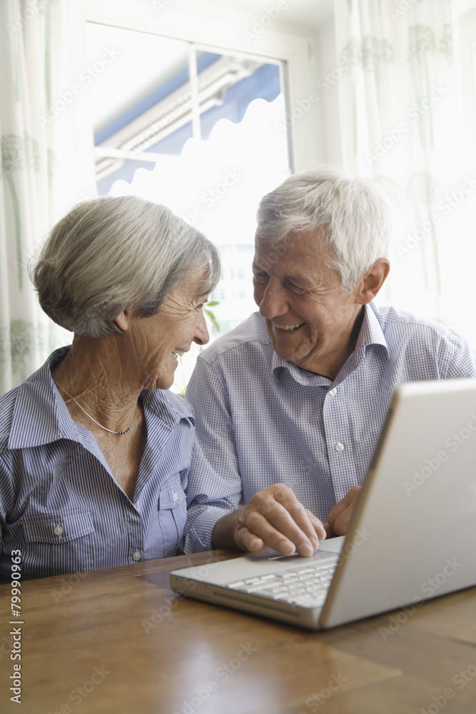 Germany, Bavaria, Senior couple using laptop at home, smiling Germany, Bavaria, Senior couple using laptop at home, smiling