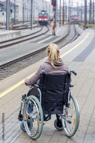 Woman in wheelchair waiting at station platform photo