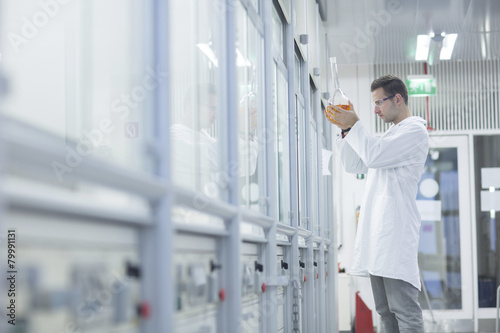 Chemist working in lab holding round bottom flask photo