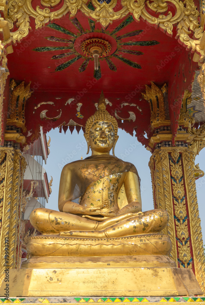 the gold buddha statue sitting under the sun light