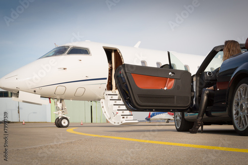 woman convertible car and corporate private jet airplane photo