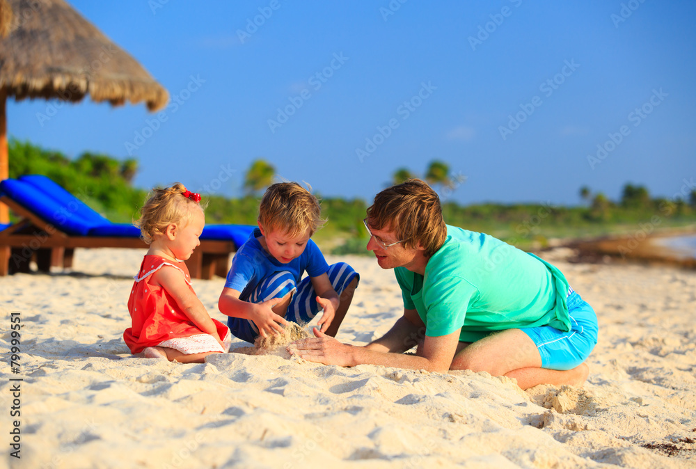 father and two kids playing with sand on beach