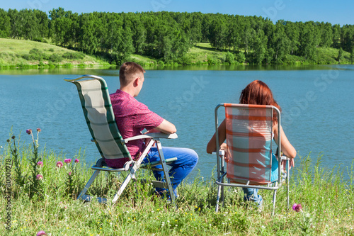 outdoor portrait of happy couples at the lake, sitting in a chai
