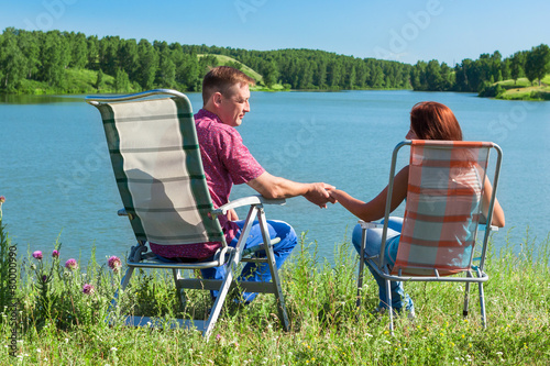 Portrait of a man and woman holding hands, sitting in chairs nea photo