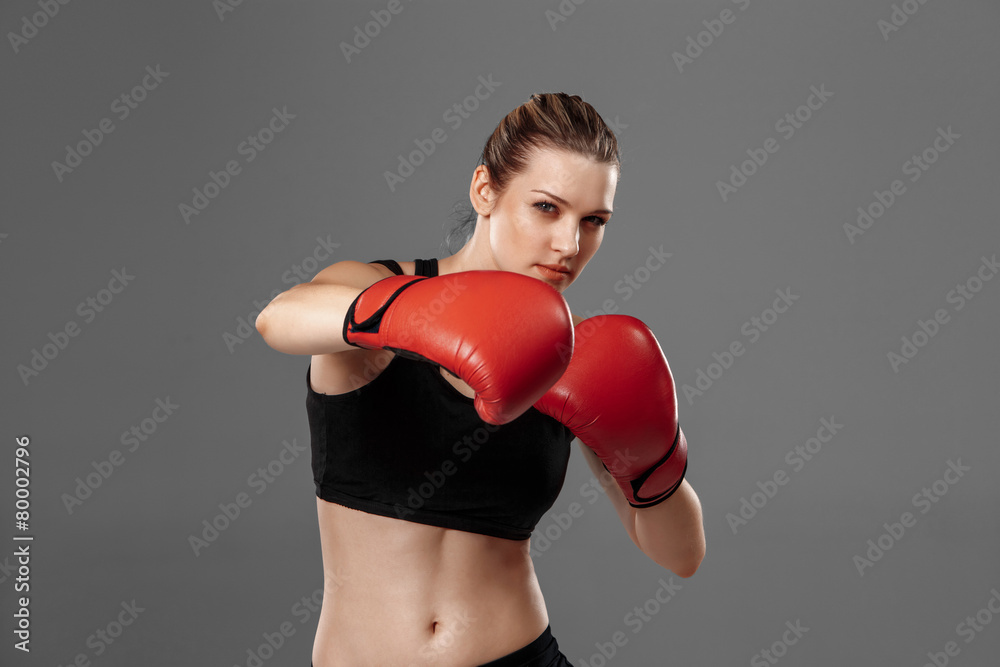 beautiful woman is boxing on gray background