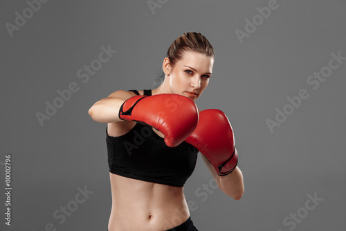beautiful woman is boxing on gray background