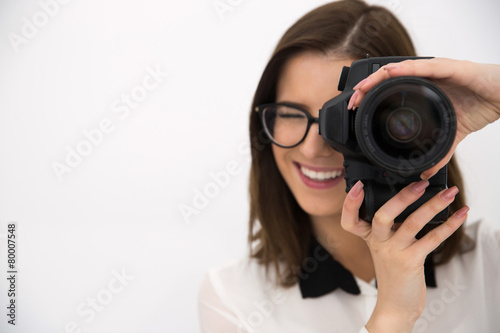 Cheerful female photographer with camera over gray background