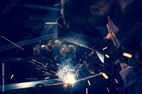 Employee at the factory welding steel using MIG MAG welder.