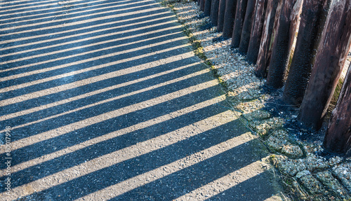 Parallel shadows of a row of wooden poles