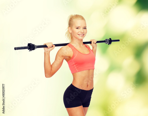 smiling sporty woman exercising with barbell © Syda Productions
