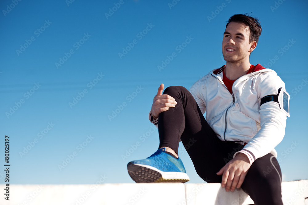 smiling athlete with armband relaxing after workout outdoors