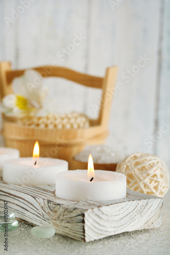Candles and bucket with spa treatment on wooden background