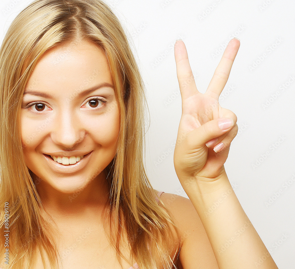 Happy smiling beautiful young woman showing two fingers or victo Happy smiling beautiful young woman showing two fingers or victo