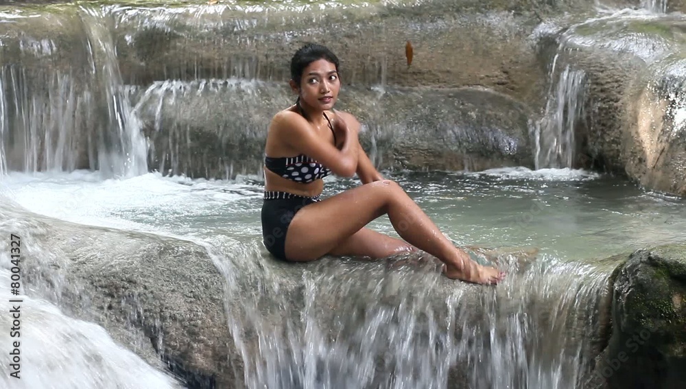 Young woman sitting in retro swimsuit in water rapids