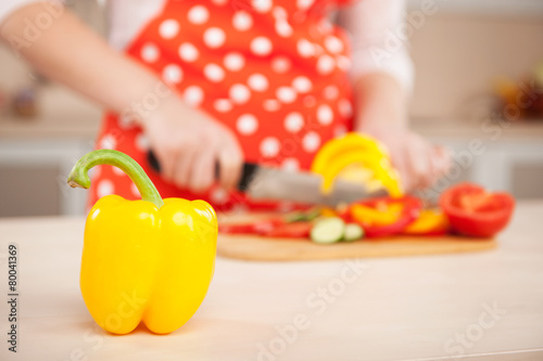 Close up photo of woman chopping yellow paprika