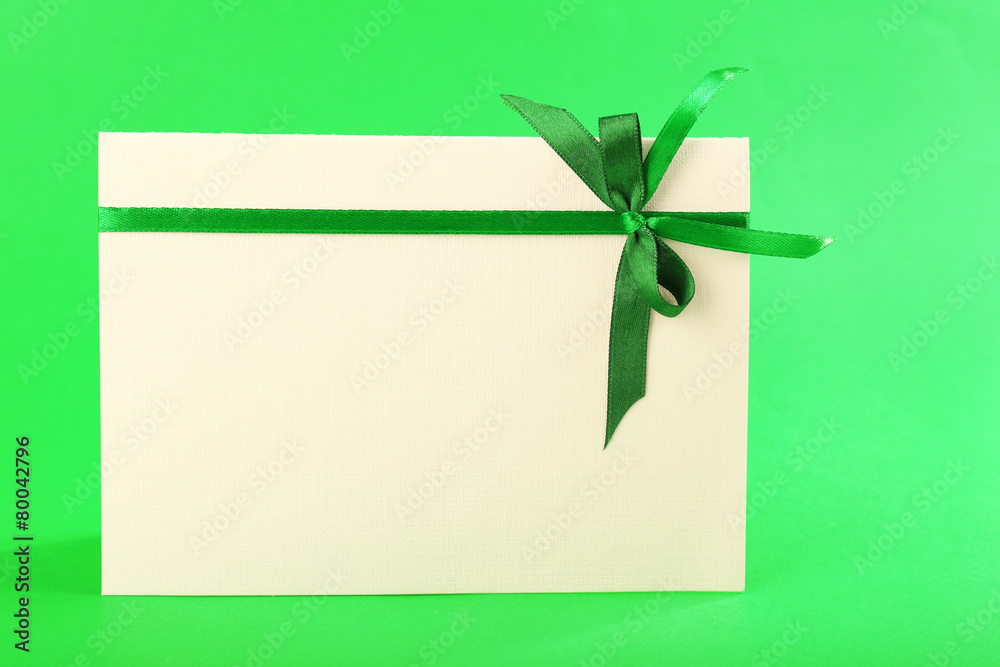 Card decorated with bow on green background Card decorated with bow on green background