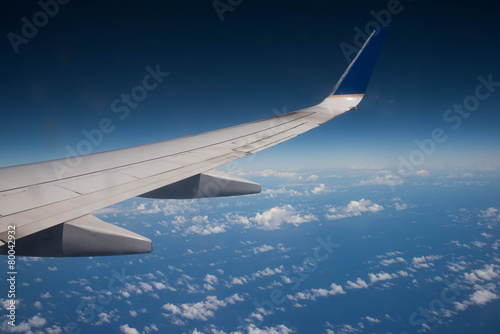 Airplane wing above the ocean blue