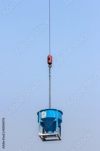 blue cement bucket is lifting on crane hook in construction site