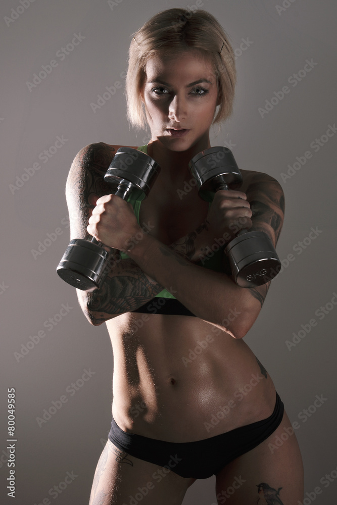 Fototapeta premium Young blonde female fitness model posing in studio.