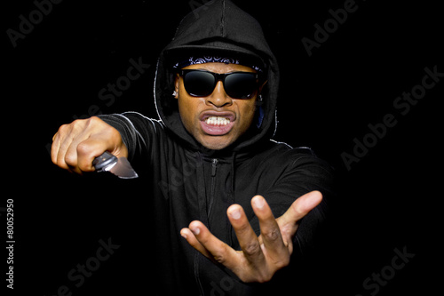 thug holding a knife coming out of the shadows photo