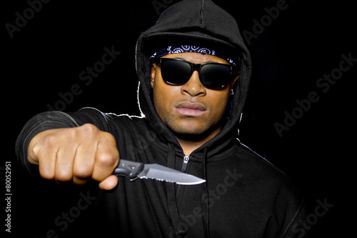 Foto thug holding a knife coming out of the shadows