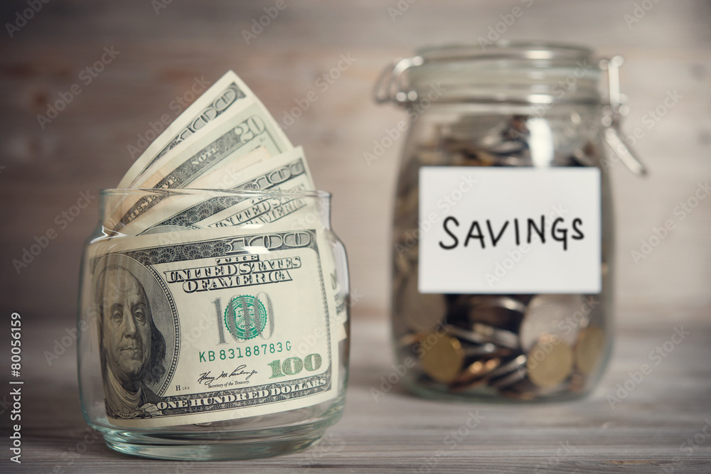 Dollars and coins in jar with saving label Dollars and coins in jar with saving label