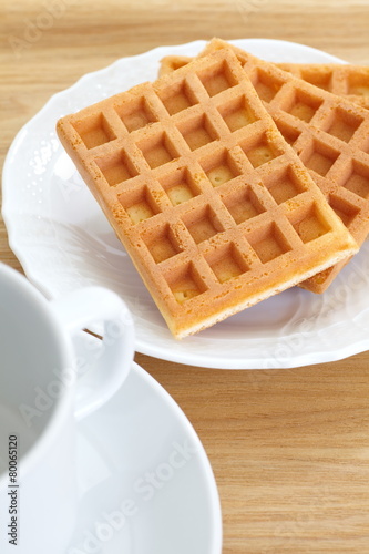 Delicious sweet waffle in white plate on wood background