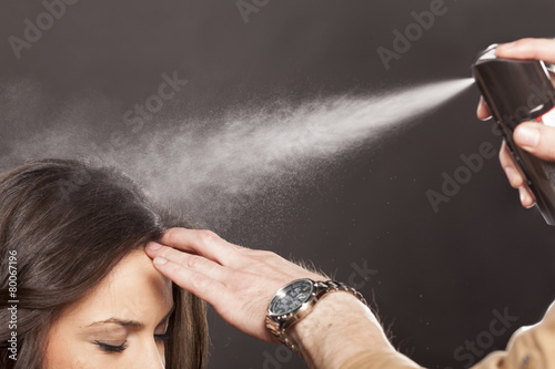 Hairdresser apply hairspray on his client's hair