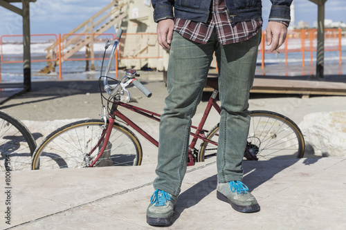 Closeup of man’s legs standing inform of a vintage bicycle