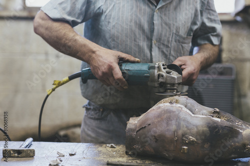 Craftsman sanding a bronze sculpture