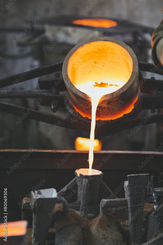 crucible pouring melted bronze into lost wax casting mold Stock Photo