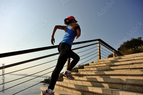  young fitness woman running on seaside stone stairs