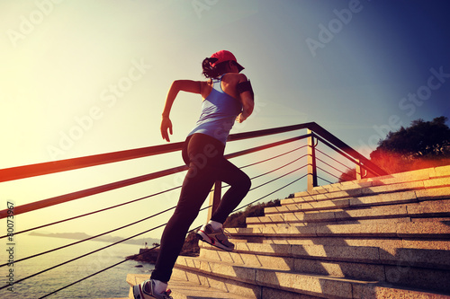 	young fitness woman running on seaside stone stairs