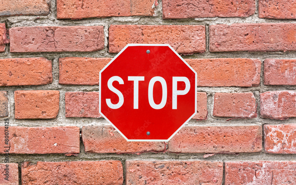 Bright stop sign attached to large brick siding Bright stop sign attached to large brick siding