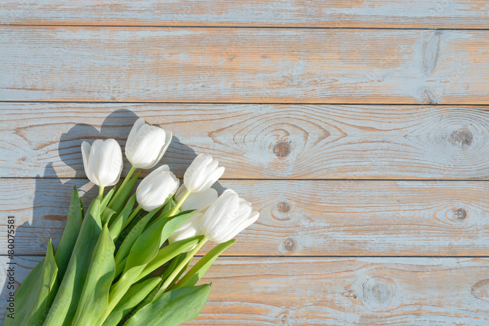 Naklejka premium Bunch of white tulips on a vintage wooden shelves planks table background with empty copy space mock up
