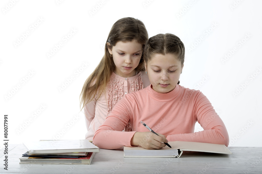 Little girls read books at the table on white Little girls read books at the table on white