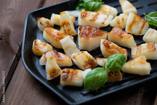 Barbecued pineapple slices with green basil on a grill, close-up