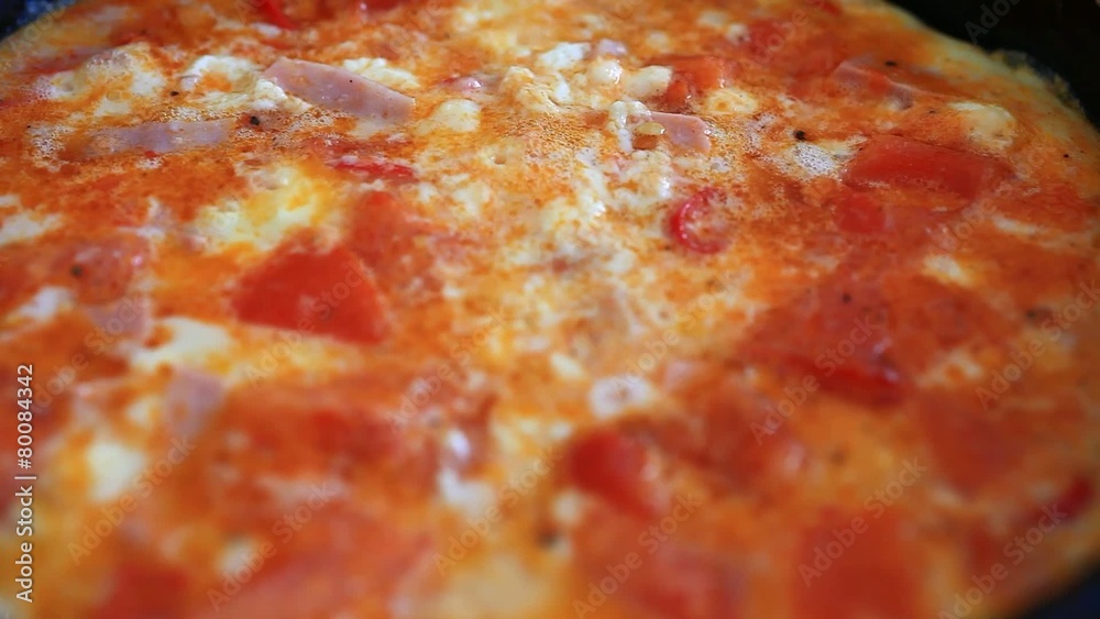 omelet with vegetables and ham fried in a pan. Close up. Macro omelet with vegetables and ham fried in a pan. Close up. Macro