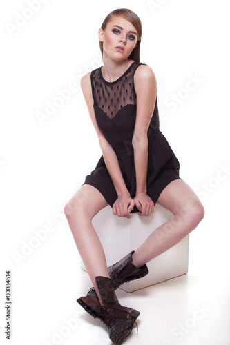 Stylish girl sitting on cube on white © rasstock