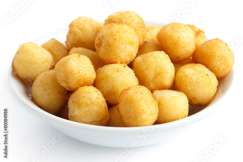 Bowl of fried small potato balls on white.