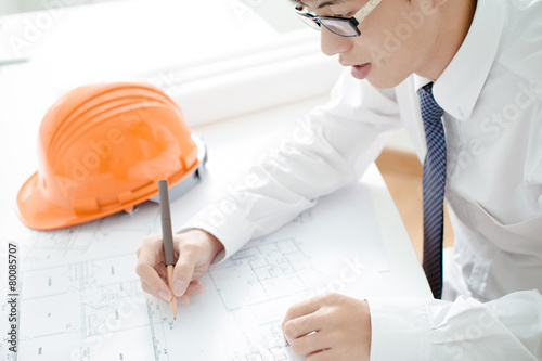Closeup cropped image of a young male architect working on bluep