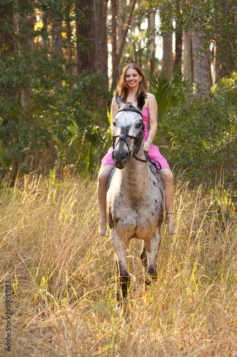 woman riding horse through forest