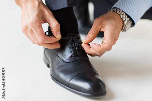 close up of man leg and hands tying shoe laces