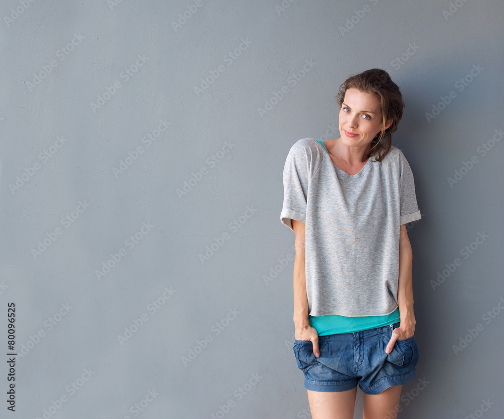 Happy cute mid adult woman standing against gray background Happy cute mid adult woman standing against gray background