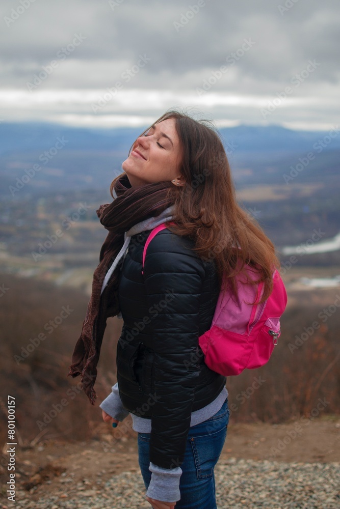 Довольная девушка в горах с розовым рюкзаком