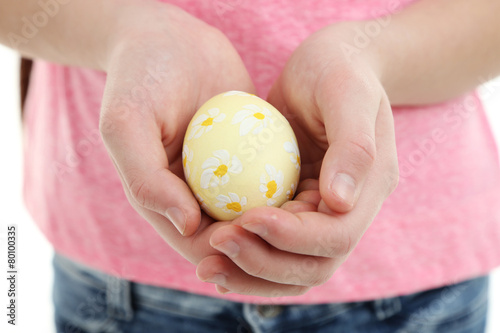 Girl holding painted egg in her hands, close-up