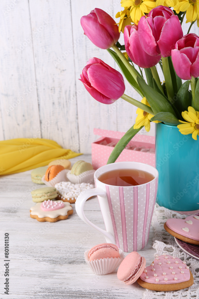 Composition of spring flowers, tea and cookies on table Composition of spring flowers, tea and cookies on table